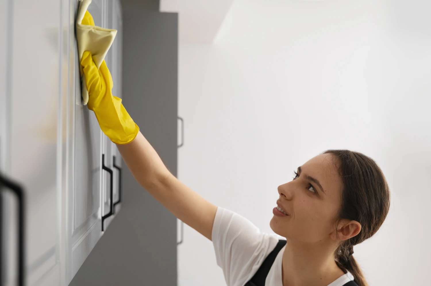 Woman wiping cabinet door with cleaning cloth Woman wiping cabinet door with cleaning cloth